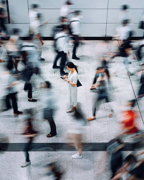 People crossing a bright concourse, blurred in motion